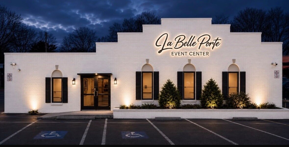 La Belle Porte Venue in La Vergne, TN at night: white brick event center with arched windows, black shutters and a lit script sign