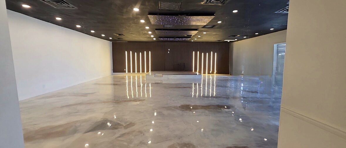 Open event hall for up to 100 guests, looking toward the stage and lit accent wall